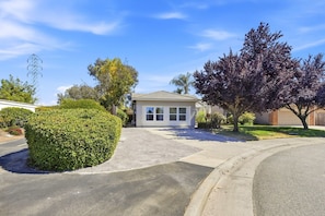 A residential property with a driveway leading to a house, surrounded by well-maintained landscaping and a clear sky.