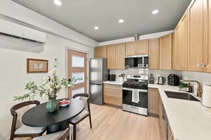 A modern kitchen with wooden cabinets, stainless steel appliances, and a dining area with a table and chairs.