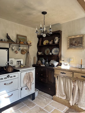 A vintage kitchen with a stove, wooden cabinets, and a chandelier. - Le Miel Cottage Romantic 1923 Forest Escape (Lake Arrowhead)
