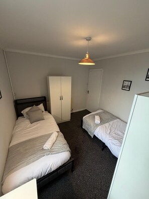 Ein Zimmer mit zwei Betten, einem Kleiderschrank und einer Deckenleuchte.