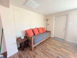 A room with a wooden bed, a bedside table, a floor lamp, and a door.