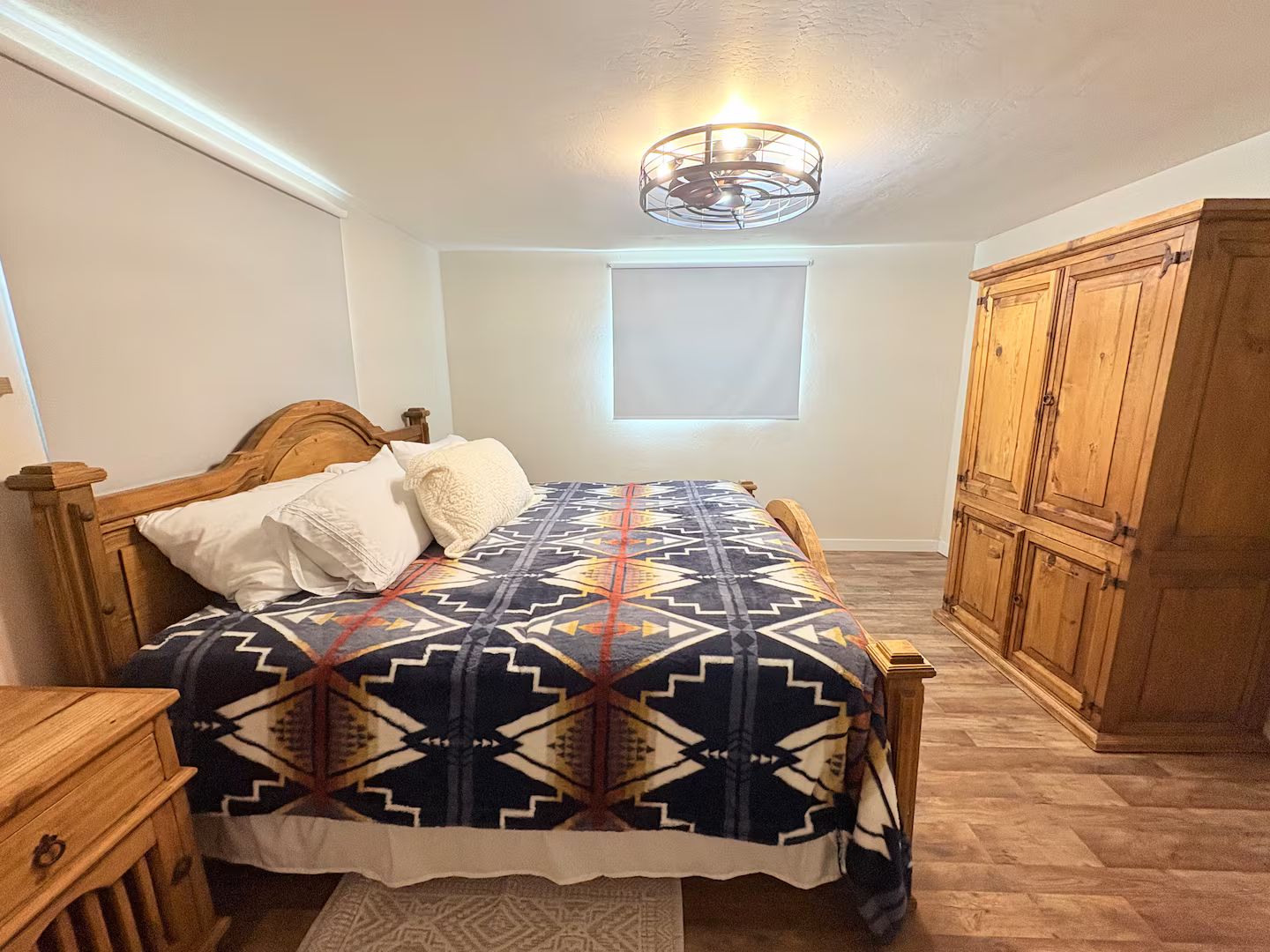 Een slaapkamer met een bed, een houten garderobe en een plafondlamp.