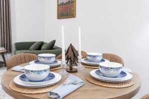 Ein runder Esstisch mit blumengemusterten Schüsseln und Tellern, einem Kerzenständer und einer gewebten Tischmatte.