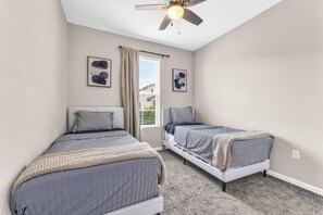 A bedroom with two beds, a ceiling fan, and a window with curtains. - Sunshine & Stay Awhile (Davenport)