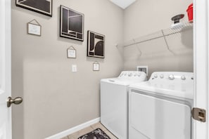 A laundry room with two white washing machines, a drying rack, and several framed pictures on the wall. - Sunshine & Stay Awhile (Davenport)