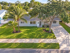 A single-story house with a front lawn, a palm tree, and a driveway leading to the entrance. - Bristo At Lantana (Lantana)