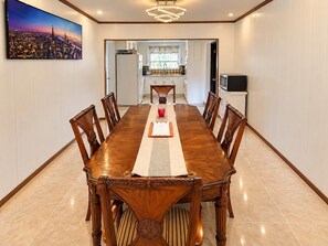 Ein Esszimmer mit einem langen Holztisch, Stühlen und einem Stadtbild an der Wand.