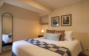 A hotel room with a bed, a nightstand, a mirror, and two framed pictures on the wall. - w* | Chic 1BR w/ Balcony in Miraflores (Miraflores)
