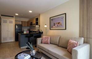 A modern living room with a sofa, a coffee table, and a kitchen area in the background. - w* | Chic 1BR w/ Balcony in Miraflores (Miraflores)