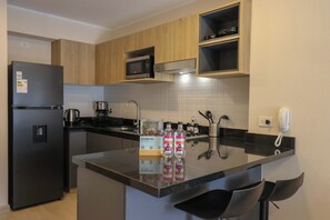 A compact kitchen with a refrigerator, microwave, coffee maker, and a small island with bar stools. - w* | Chic 1BR w/ Balcony in Miraflores (Miraflores)