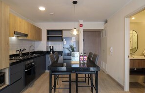 Una cocina moderna con comedor, que incluye una mesa y sillas negras, una cafetera y armarios de madera.