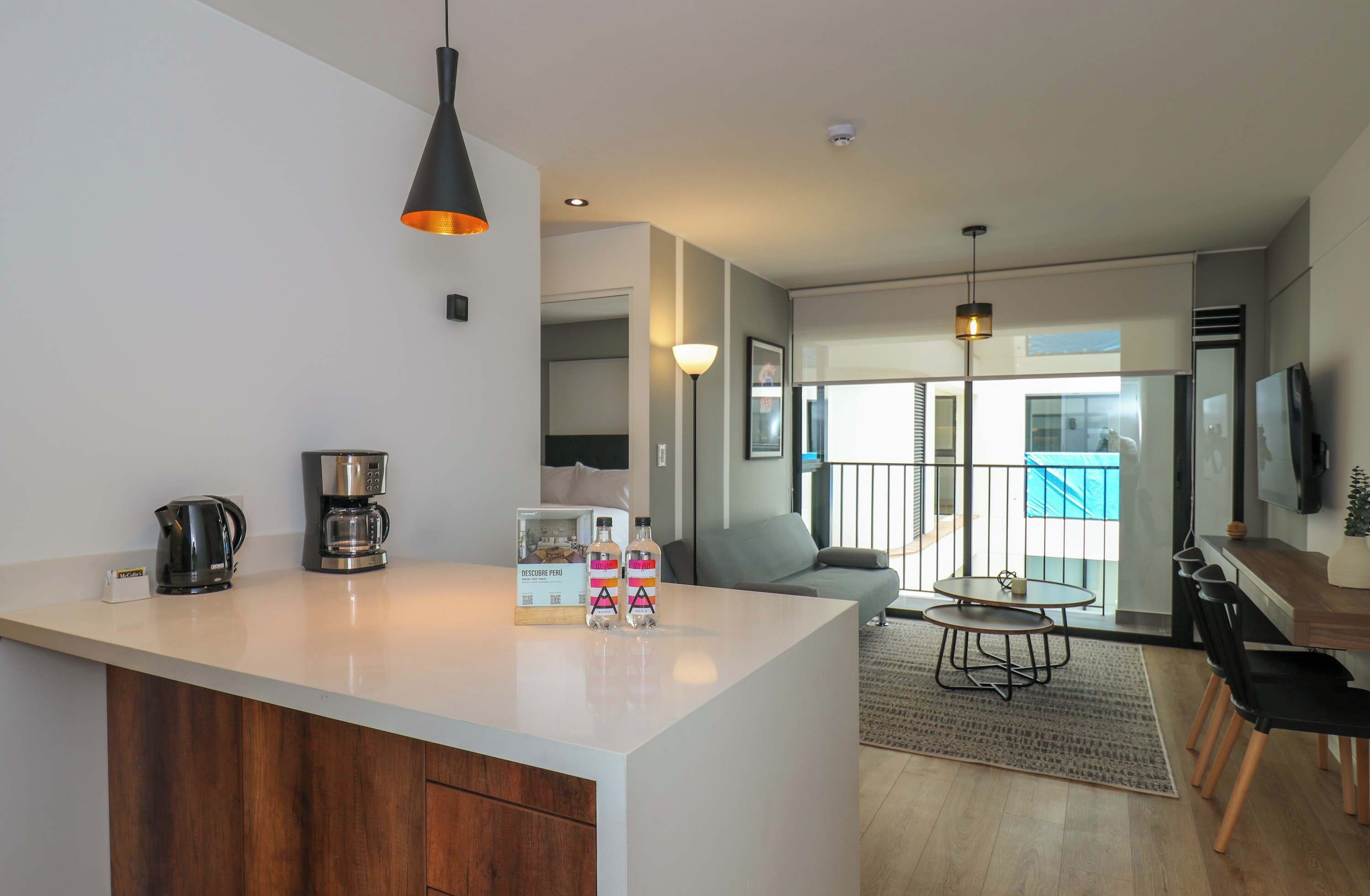 A modern kitchen with a coffee maker, a kettle, and a bottle of water on the counter.