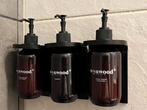 Three bottles of Wynwood House shampoo and conditioner on a tiled wall. - w* | Stylish Loft in the Heart of Chicó Norte (Bogotá)