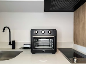 A modern kitchen with a built-in toaster oven, a stainless steel sink, and a black faucet. - w* | Stylish Loft in the Heart of Chicó Norte (Bogotá)