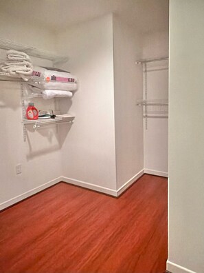 A corner of a room with a wooden floor, white walls, and two shelving units against the wall. - 2-BD Private Entry 2 Parking Space Corporate apartment in fabulous Downtown SD (San Diego)