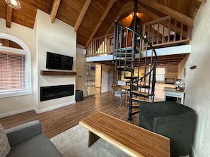 A spacious loft with a wooden staircase, a flat-screen TV, and a fireplace. - Cozy Cabin with a Fireplace and a Hot Tub (flagstaff)