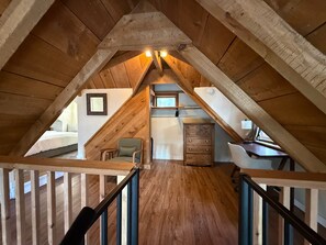 A wooden attic bedroom with a sloped ceiling, a desk, a chair, and a dresser. - Cozy Cabin with a Fireplace and a Hot Tub (flagstaff)