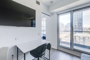 A modern office space with a white desk, black office chair, and a large window offering a city view. - Downtown Toronto Condo Suite next to Eaton Centre (Toronto)