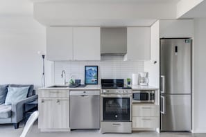 A modern kitchen with stainless steel appliances, a dishwasher, and a built-in oven. - Downtown Toronto Condo Suite next to Eaton Centre (Toronto)
