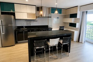 A modern kitchen with a central island, stainless steel appliances, and a view of greenery outside. - New Listing (São Paulo)