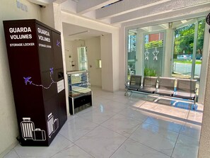 A hotel lobby with a glass door entrance, a seating area with chairs, and storage lockers labeled 'GUARDA VOLUMES'. - New Listing (São Paulo)