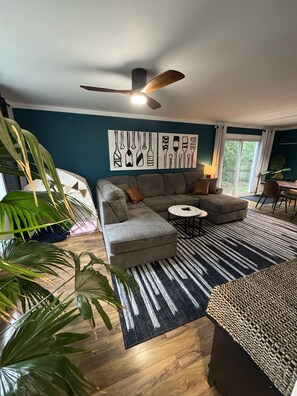A modern living room with a sectional sofa, a round coffee table, and a ceiling fan. - North Nook (Barrie)