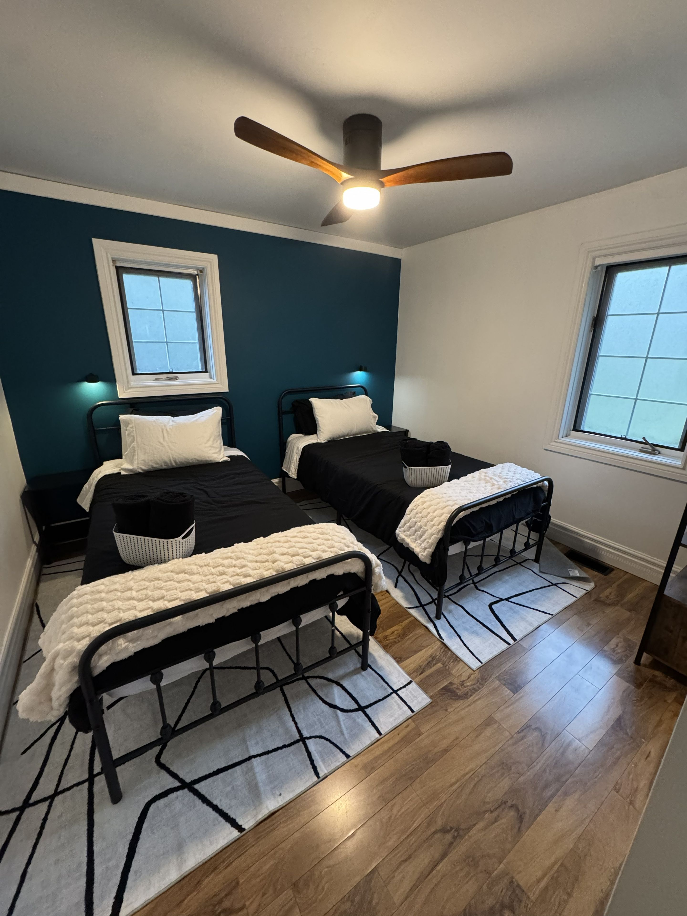A bedroom with two beds, a ceiling fan, and a window.