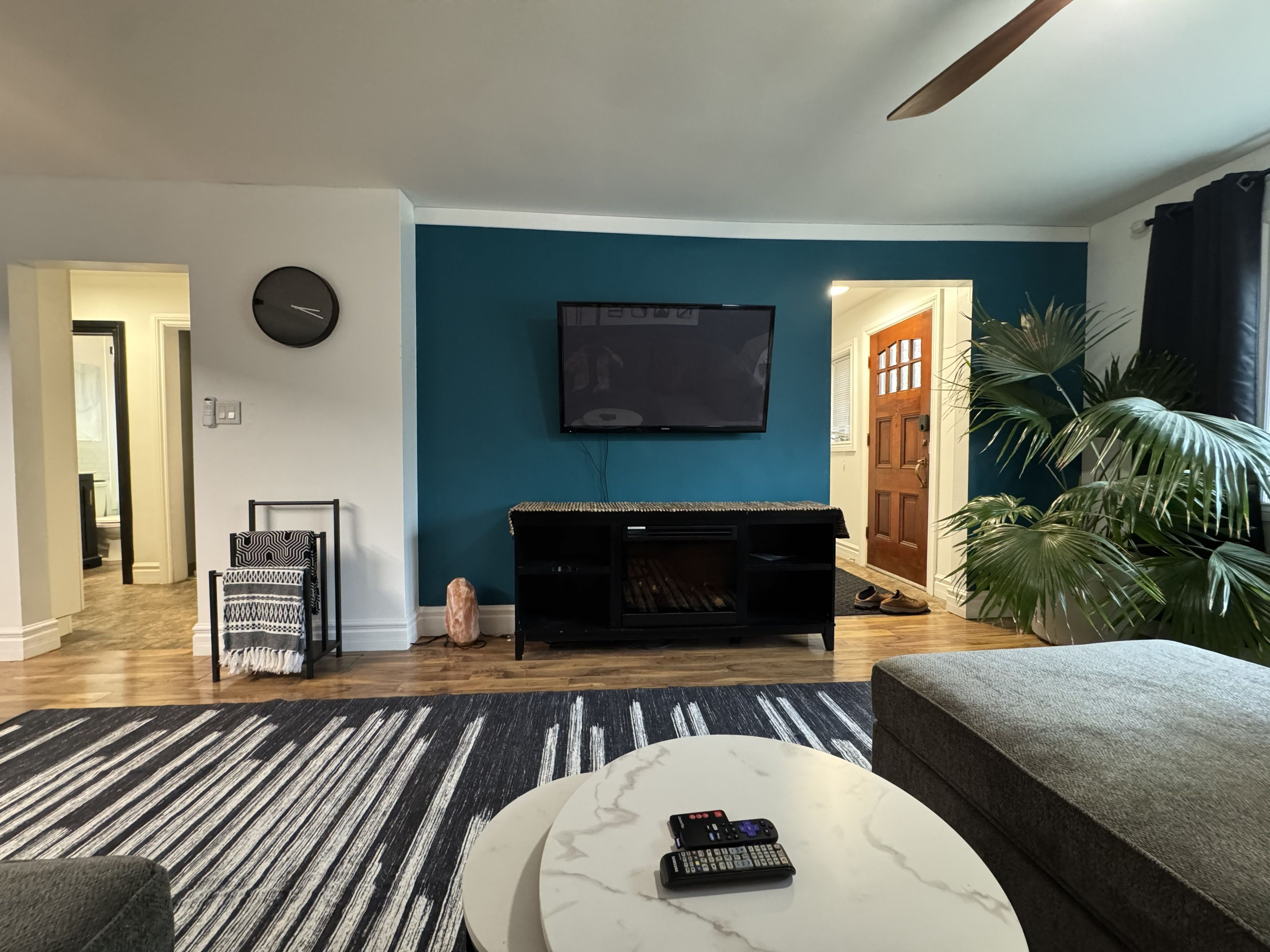 A living room with a television mounted on the wall, a sofa, a coffee table, and a patterned rug.