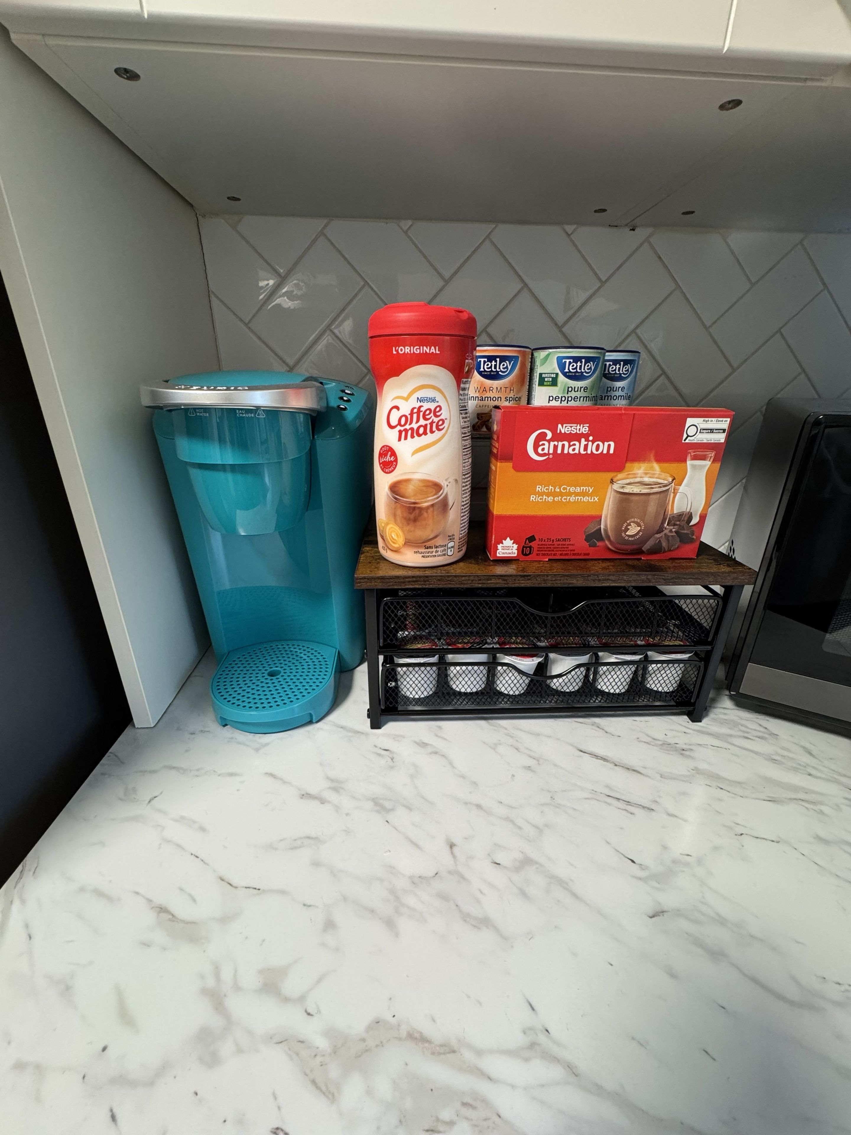 A kitchen counter with a water dispenser, coffee products, and a spice rack.