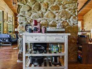 A rustic kitchen with stone walls, wooden cabinets, and various kitchen appliances. - Cozy Cabin & Guest House Hot Tub, Firepit, Games sleeps 12 (Towns County)