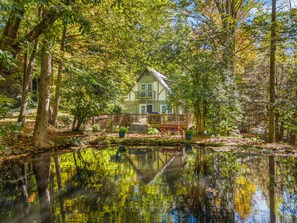 A house with a balcony, surrounded by trees and a pond. - The Koi Cottage: Hot Tub - Treehouse - BIG Pond. 5 years as a top rated retreat! (Maggie Valley)