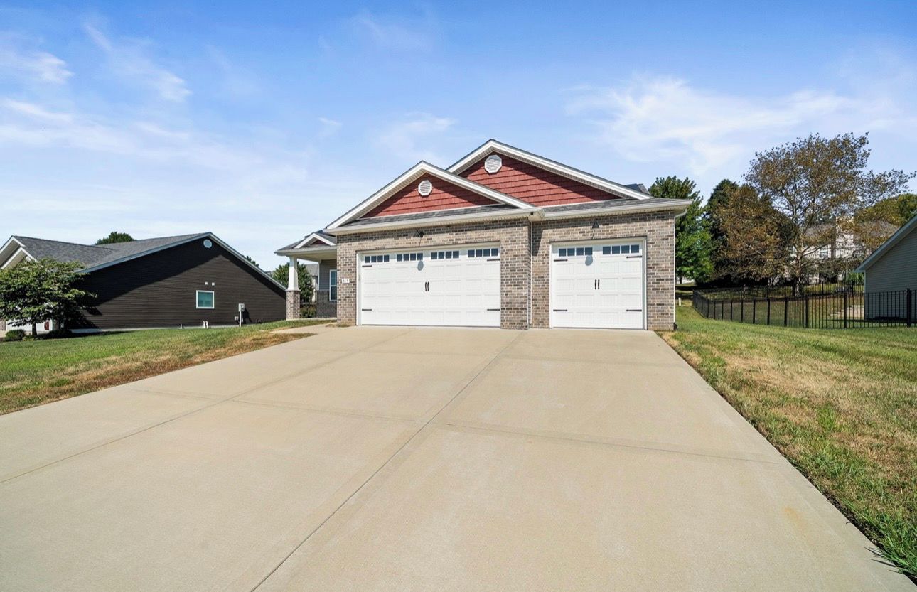 A two-story house with a garage, a driveway, and a fenced yard.