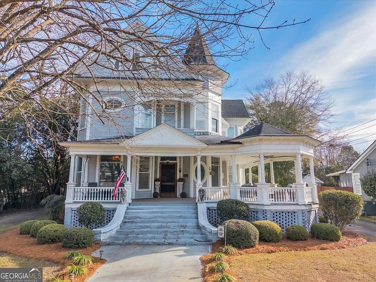 A two-story house with a porch, a small gazebo, and a flag.