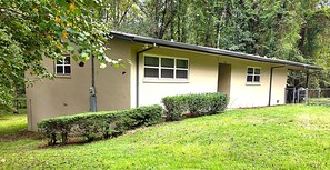 A single-story building with a flat roof, a small front porch, and a well-maintained lawn. - Neal Street Retreat - Welcoming Home, Perfect for Families and Getaways (Tuskegee)