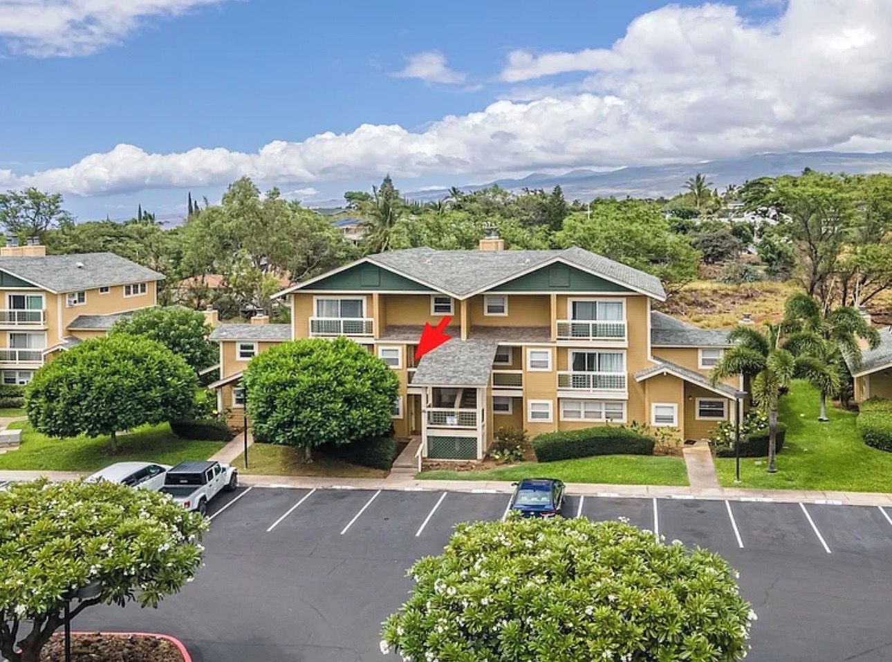 A multi-story residential building with a parking lot in front.