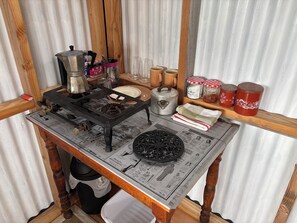 A kitchen counter with a stove, pots, a coffee maker, and various kitchen items. - The Stoney Shore - boutique lakeside camp. Breathtaking lake mountain views (Te Anau)