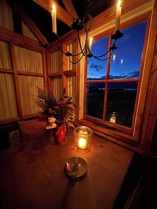 A room with a wooden interior, a window with a view of the sky, and a table with a candle and a plant.