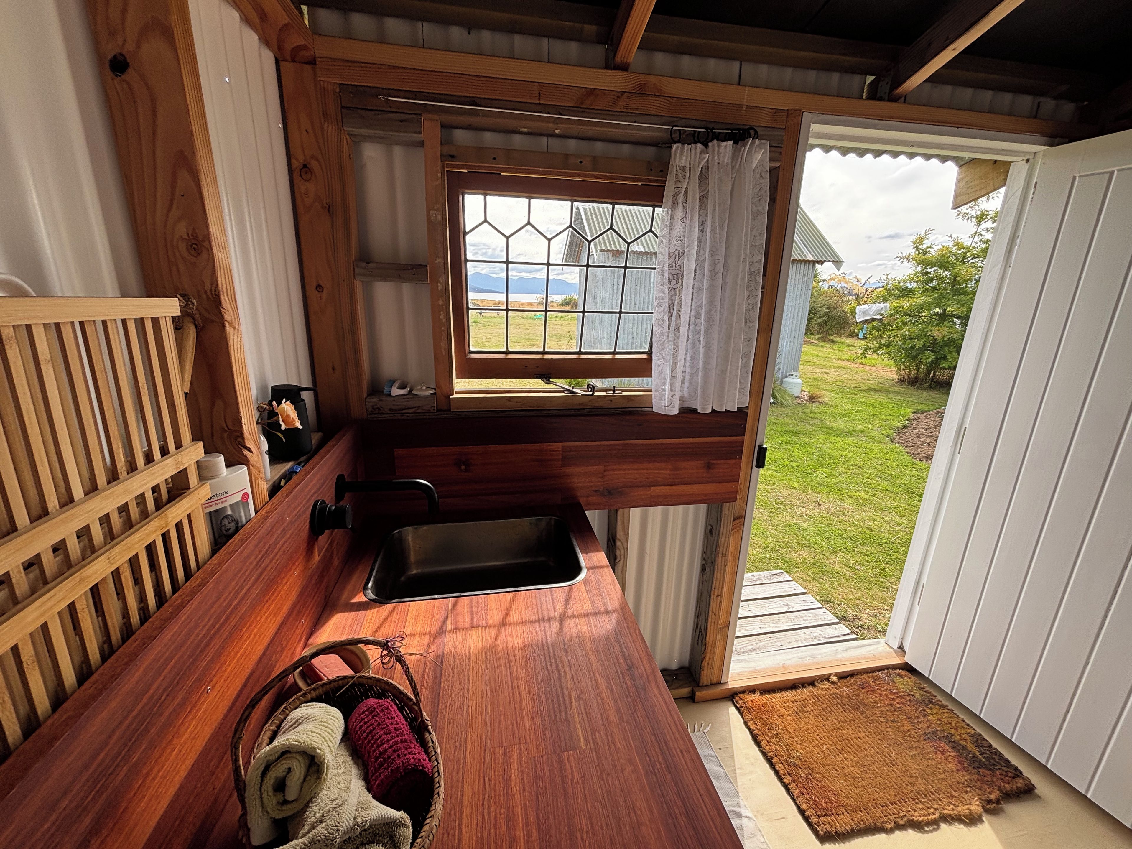 A compact kitchen with a wooden countertop, a sink, and a window with a view of the outdoors.