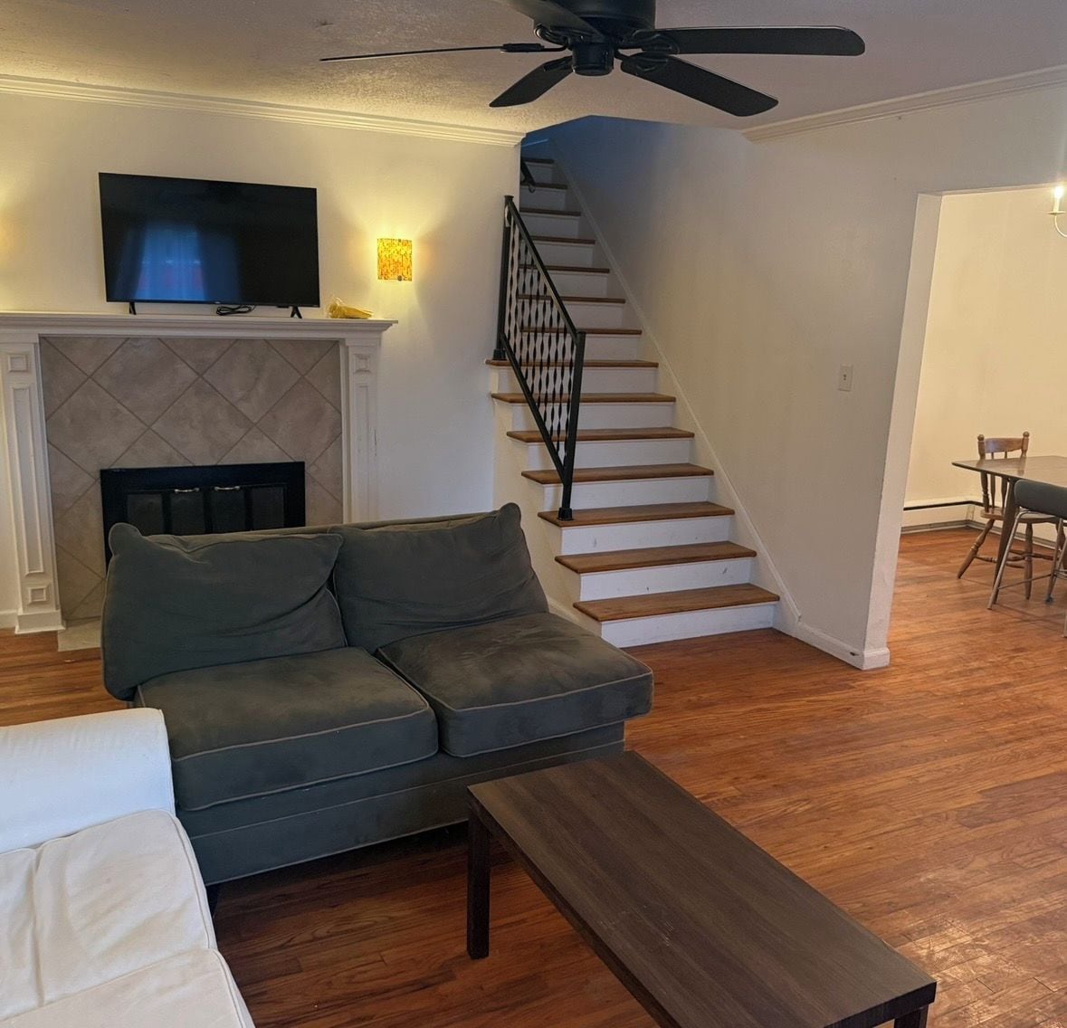 Un salon avec un canapé, une table basse, une cheminée, un téléviseur et un escalier.