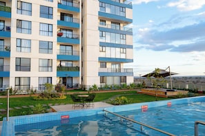 A hotel with a swimming pool, outdoor seating, and a view of the landscape. - Stylish 1 Bedroom Retreat, with a Pool, Gym and Close to the Airport (Nairobi)