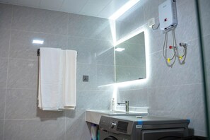 Une salle de bain équipée d’un miroir, d’un porte-serviettes, d’un lavabo et d’un chauffe-eau.