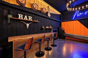 A bar area with wooden bar counter, bar stools, and a neon sign. -     10-Acre Resort Ranch & Venue, Pool, Hot Tub, Game Barn, Theater Sleeps 30 (Wimberley)
