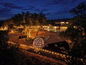 A nighttime view of a resort with a swimming pool, lounge chairs, and a large spherical structure. -     10-Acre Resort Ranch & Venue, Pool, Hot Tub, Game Barn, Theater Sleeps 30 (Wimberley)
