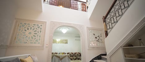 A multi-level interior with ornate architectural details, a staircase with patterned railings, and a checkered floor.