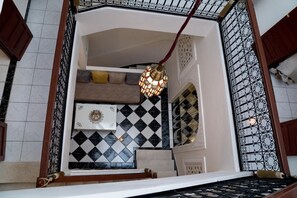 A staircase with a patterned floor, a decorative wall hanging, and a hanging light fixture. - New Listing (Marrakech)