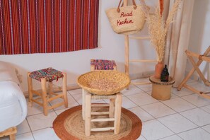 A room with a wooden stool, a woven basket, a hanging bag, and a small table with a bottle. - New Listing (Marrakech)