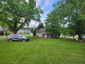 A residential area with a house, a parked car, and a grassy lawn. - Train Tracks Getaway - 2-bedroom house in peaceful Odenton close to MARC (Odenton)