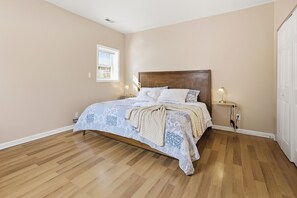 A bedroom with a wooden bed, a nightstand, a lamp, and a window. - Train Tracks Getaway - 2-bedroom house in peaceful Odenton close to MARC (Odenton)
