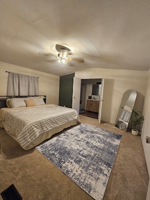 A bedroom with a bed, a ceiling fan, a large rug, and a mirror. - Bass & Jellyfish Retreat 3BR, 2BA Sleeps More with Flexible 4-Bedroom Setup (Athens)