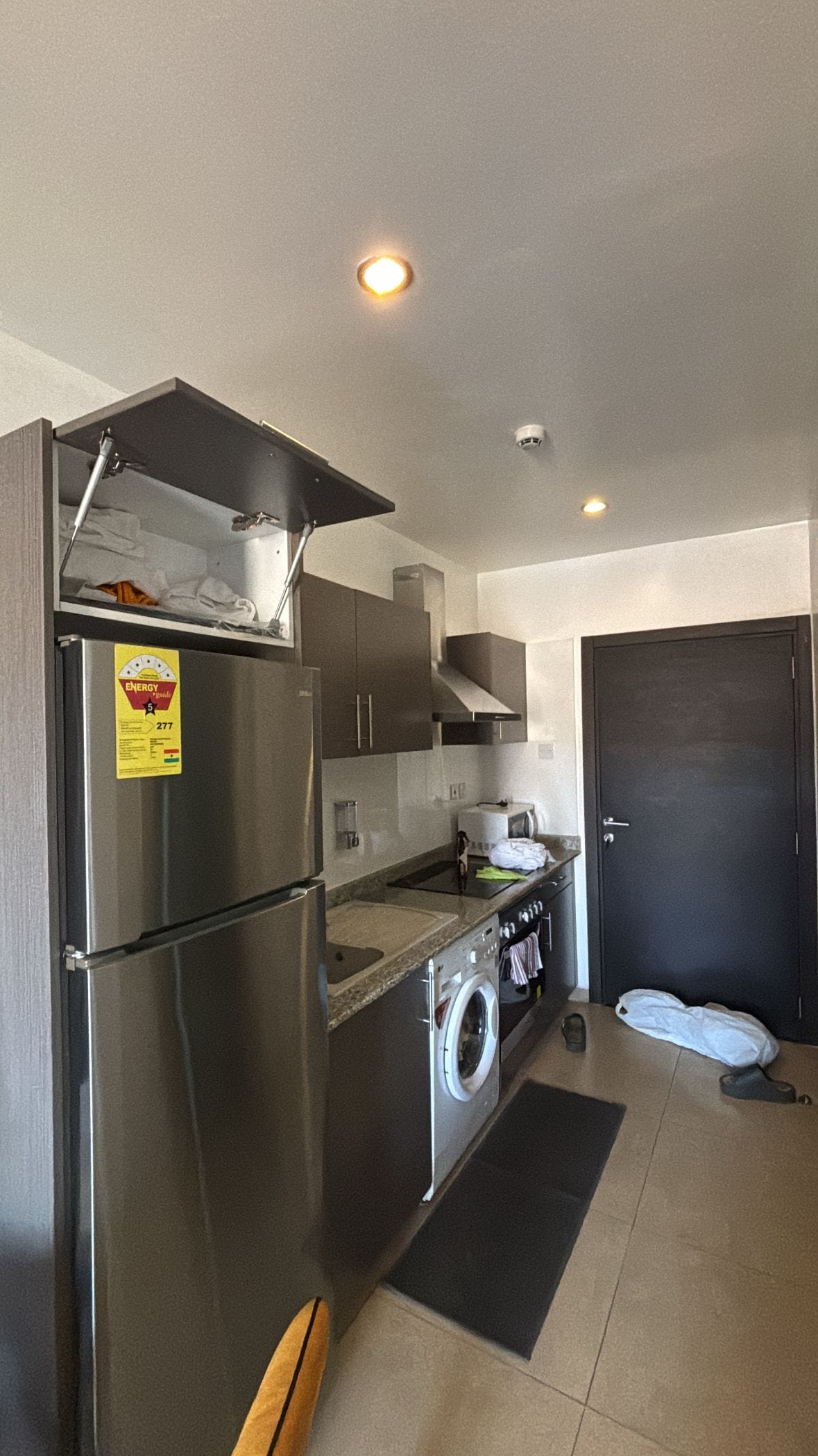 A compact kitchen with a refrigerator, microwave, oven, and washing machine.